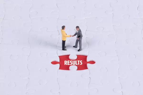 Two miniature man shaking hands and a missing puzzle piece with Results text