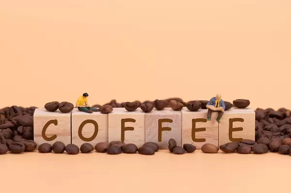 Two miniature man sitting an reading at the Coffee text