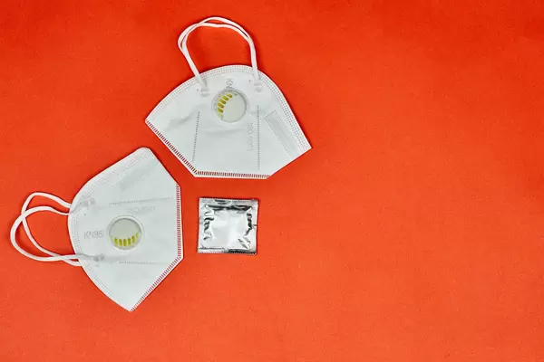 Two N95 face masks and condom on red