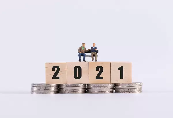 Two older man sitting on wooden cubes with 2021 text