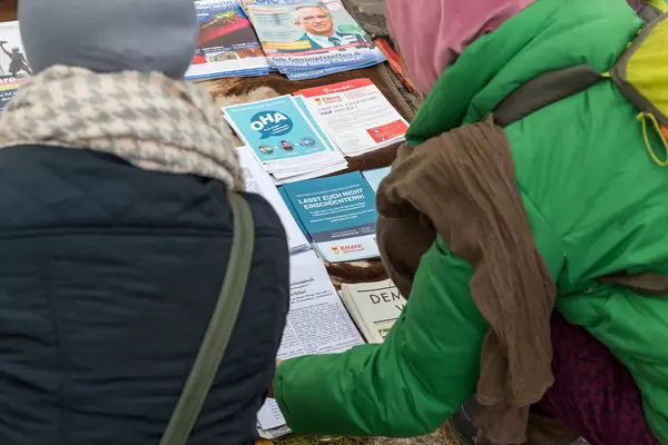 Two participants at the demonstration against the Covid rules on 11.11. in Cologne read flyers on display