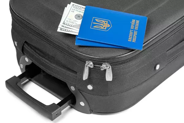 Two passports with dollars inside lie on a packed suitcase