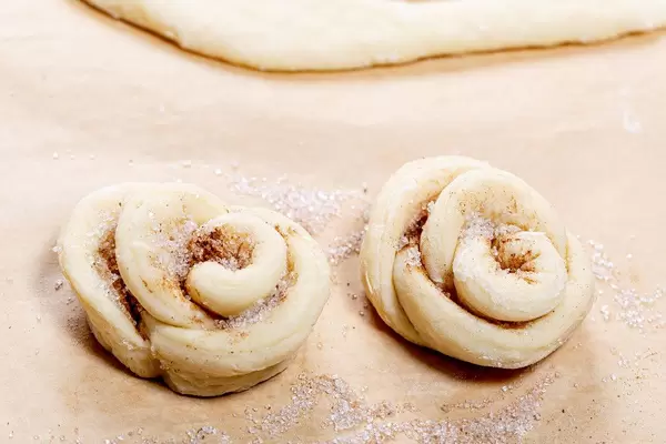 Two raw buns with cinnamon and sugar in the shape of flowers