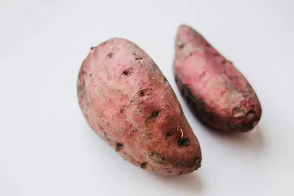 Two red potatoes on white background.
