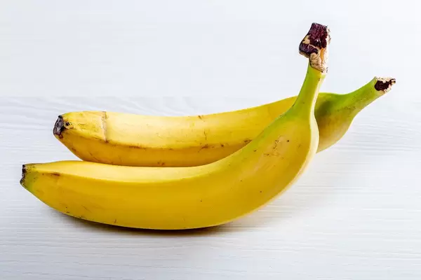 Two ripe bananas on a white wooden table (Flip 2019)