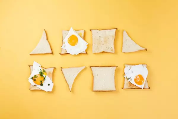 Two rows of toasts in different shapes with fried eggs. Minimalistic food styling