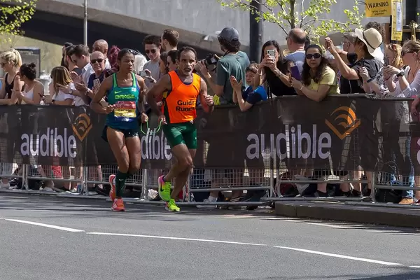 Two runners running side by side and holding green rope - London Marathon 2018