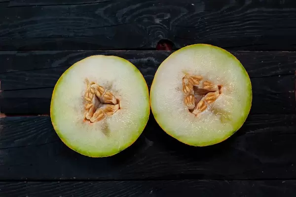 Two slice of sweet melon on the dark wooden background.jpg