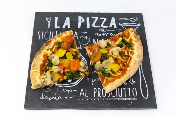 Two slices of the Veganz Verdura pizza with mushrooms, tomatoes, spinach and paprika on a black plate