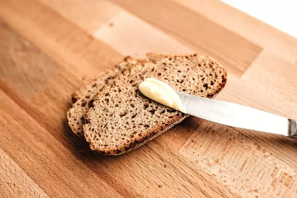 Two slices of typical German dark bread with butter on a knife