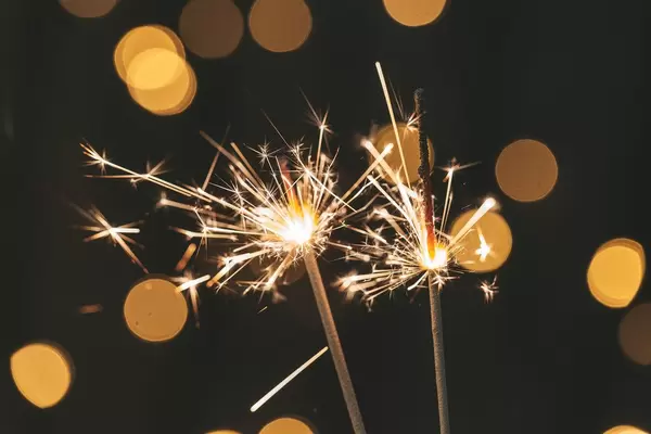 Two sparklers are lit on a blurred background of a glowing garland (Flip 2019)