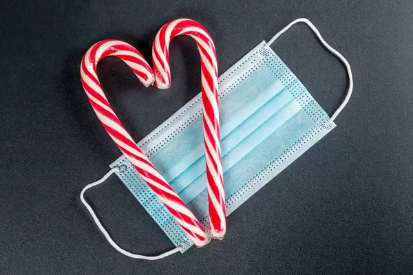 Two striped lollipops and a medical mask on a black background, top view