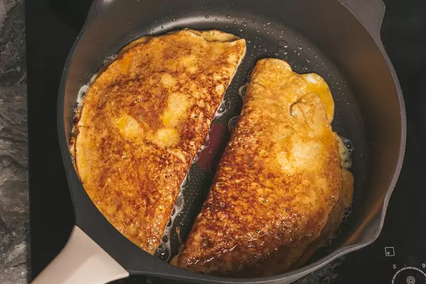 Two stuffed omelets are fried in a skillet