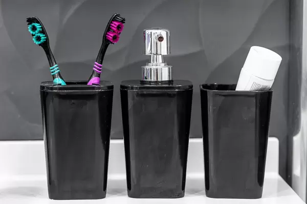 Two toothbrushes and a toothbrush with a bottle of liquid soap in the bathroom