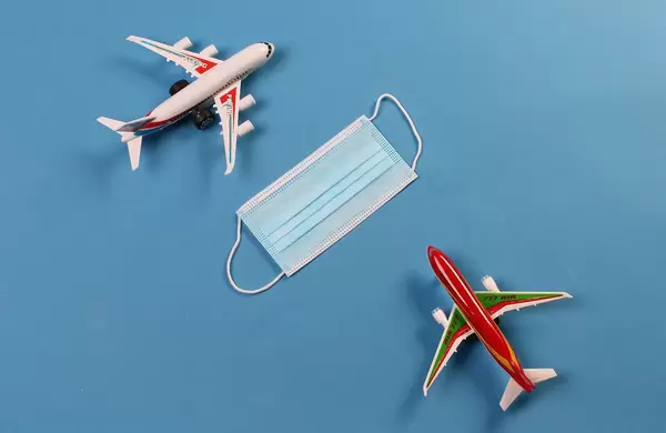 Two toy airplanes with medical face mask on blue background