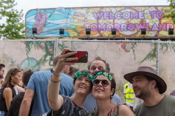 Two women taking a selfie with the 'Welcome to Tomorrowland' sign at Tomorrowland festival in Belgium