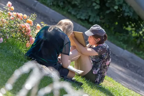 Two young women sitting on grass and painting in Gorky Park