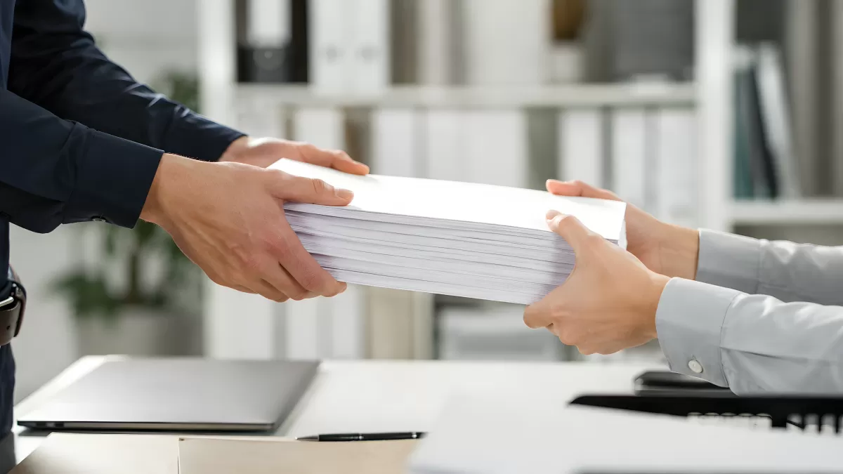 Übergabe eines großen Papierstapels im Büro