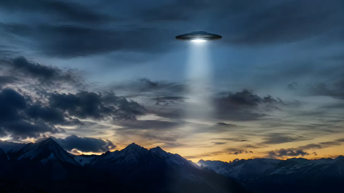 UFO mit Lichtstrahl über verschneiten Bergen