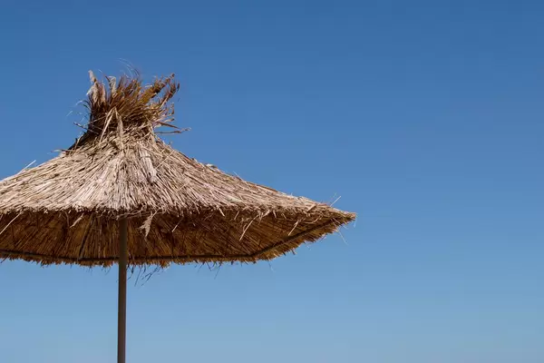 Umbrella made of straw at blue sky background