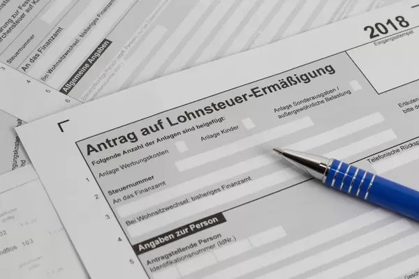 Unausgefüllter Antrag auf Lohnsteuer-Ermäßigung diagonal mit blauen Kugelschreiber in Nahansicht