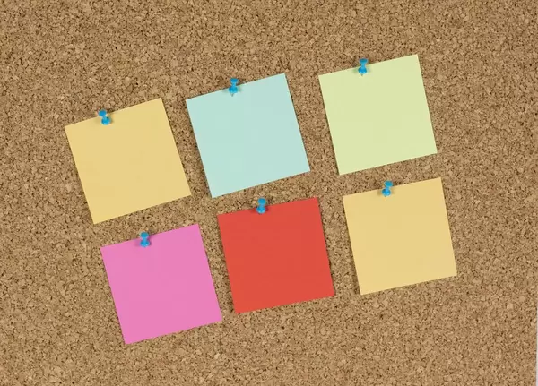 Unbeschriftete Klebezettel auf einer Wandtafel aus Kork