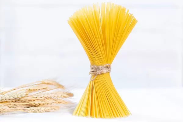 Ungekochte Spaghetti zu Bund geschnürt neben Weizen