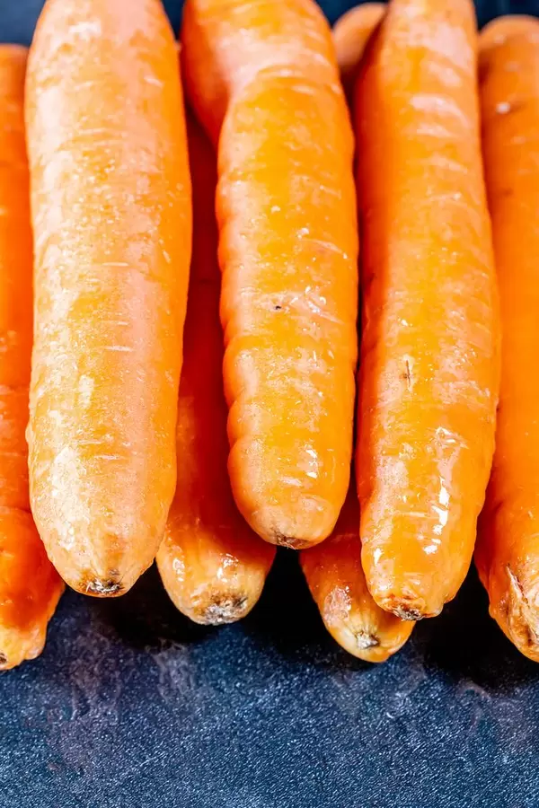 Ungeschälte und rohe Karotten für gesunde Ernährung mit Carotin auf dunklem Hintergrund