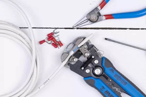 Unior Crimp Grip Pliers above white background table with wire and pliers