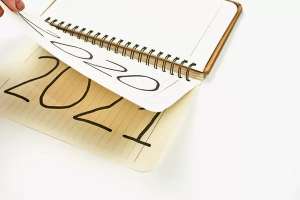 Unrecognizable person fingers flipping notepad sheet turning 2020 to 2021