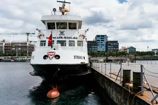 Up close picture of a ship at Kiel’s port in front of modern buildings