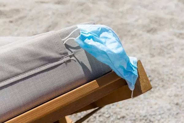 Urlaub in Zeiten der Corona-Pandemie: Mundschutz auf Sonnenliege am Strand im Sommer 2020