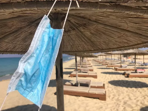 Urlaub während Corona: Mundschutz hängt an einem Sonnenschirm am Maragkas-Strand von Naxos, Griechenland