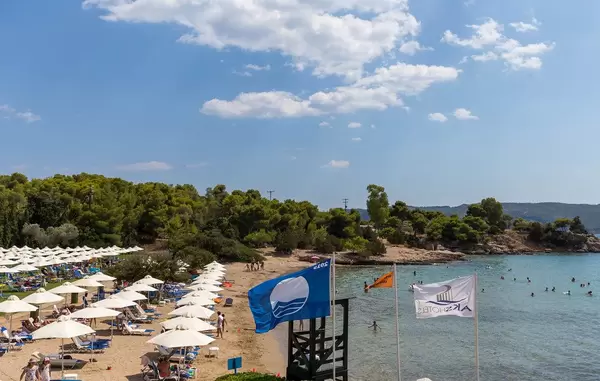 Urlauber am Strand des Aks Hinitsa Bay Hotels in Chinitsa, mit Strandliegen und weißen Sonnenschirmen