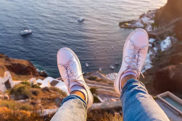 Urlaubsgefühl in Griechenland: am Rande der Klippe sitzen. Füße hängen in der Luft über dem Meer