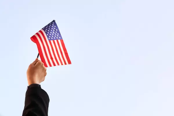 US-Politik: eine Hand hält das Sternenbanner hoch. Weißer Hintergrund mit Platz für Text