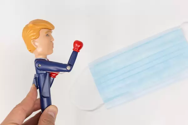 USA-Coronakrise: Trump-Figur schnellt der Arm mit Boxhandschuh nach vorne vor dem Mundschutz