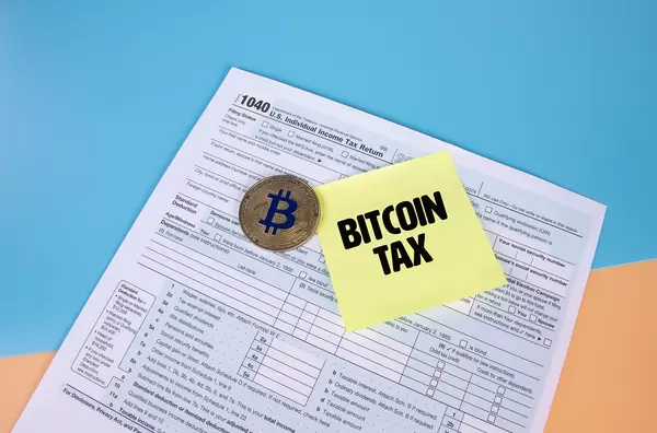 USA tax form 1040 for US individual tax return with golden Bitcoin and sticky note with Bitcoin Tax text