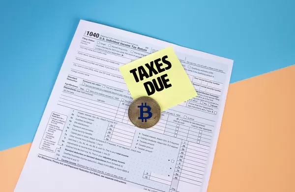 USA tax form 1040 for US individual tax return with golden Bitcoin and sticky note with Taxes Due text