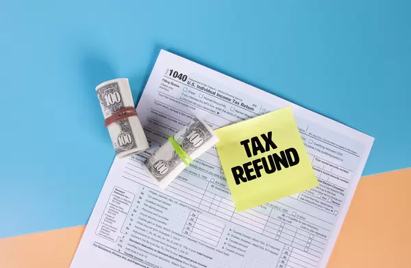 USA tax form 1040 for US individual tax return with money rolls and sticky note with Tax Refund text