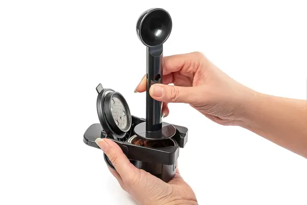 Using a tamper to press freshly ground coffee into a coffee tablet