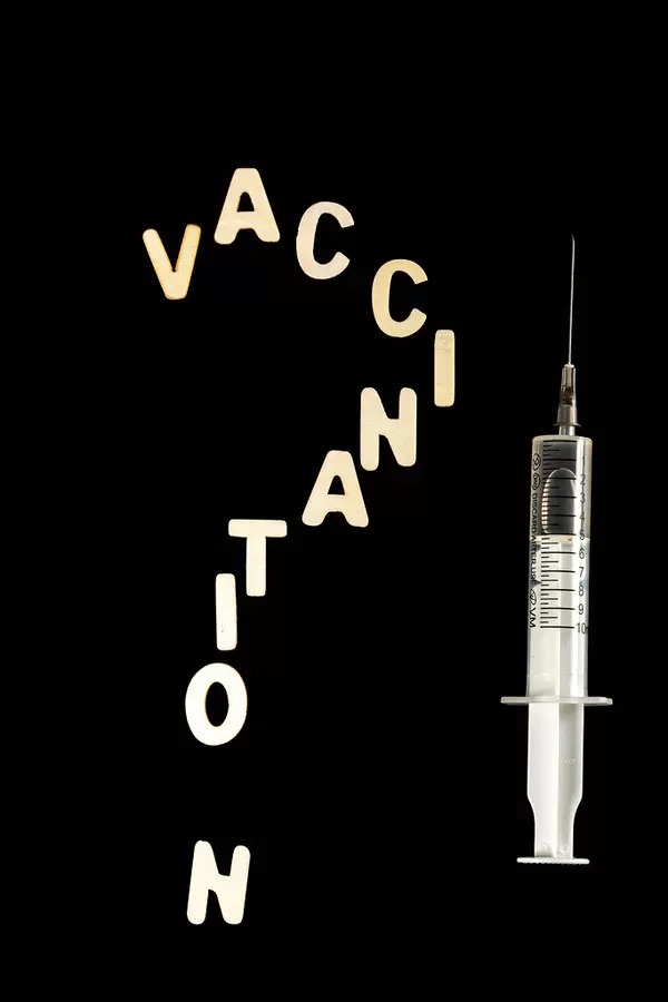 Vaccination question on dark background and syringe with vaccine