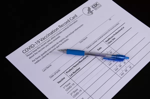 Vaccination record card with pen on black table