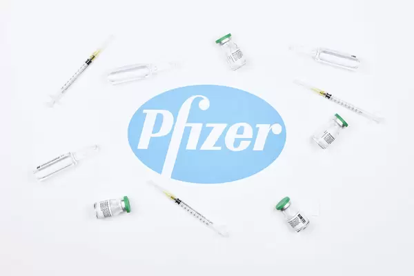 Vaccine doses and syringe for injection around the Pfizer logotype