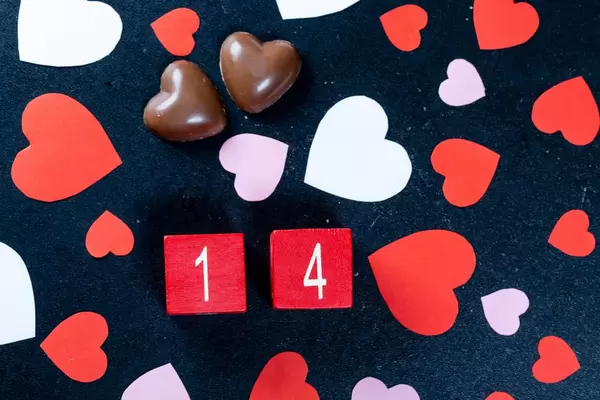 Valentine's date with chocolate and paper hearts on black background