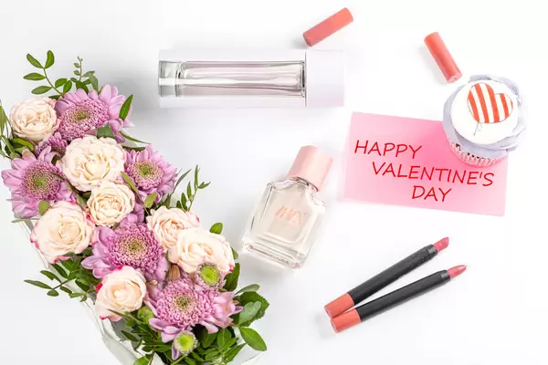 Valentine's day background with flowers, lipsticks, perfume and cupcake