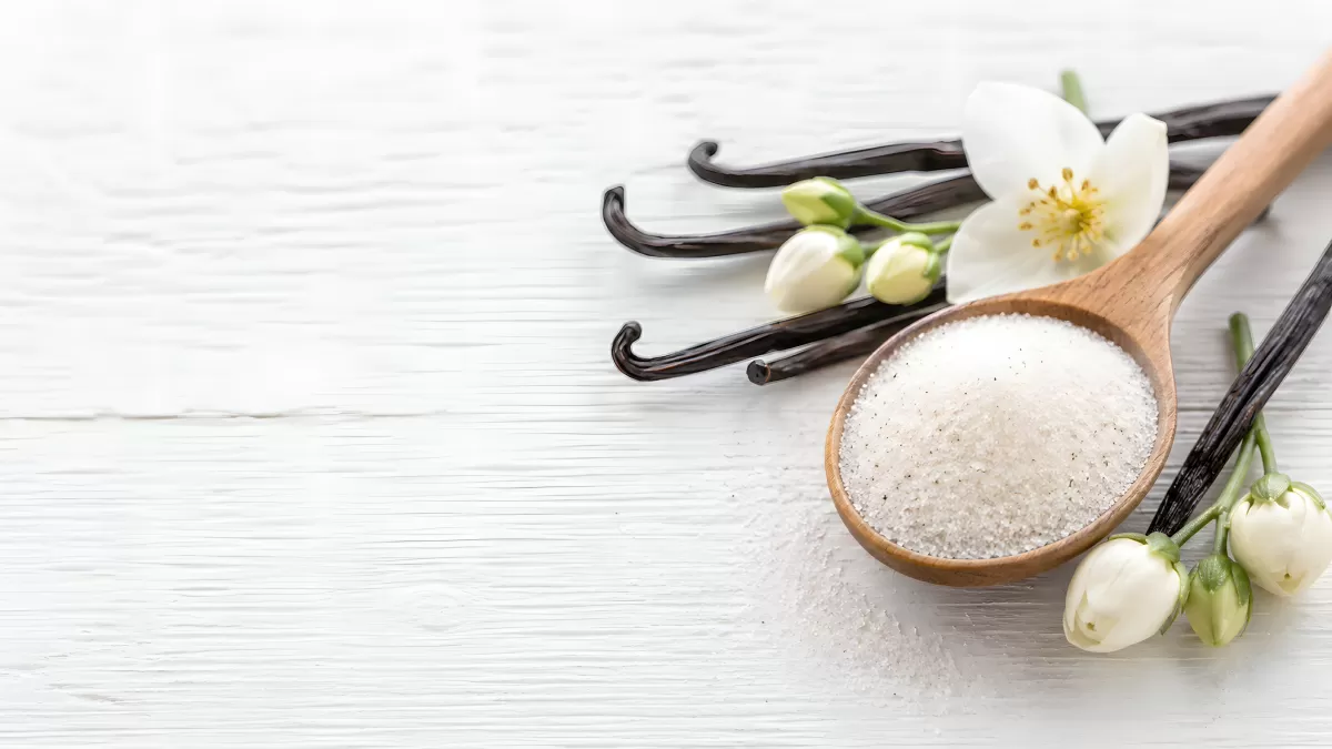 Vanillezucker im Holzlöffel mit Schoten und Blüten