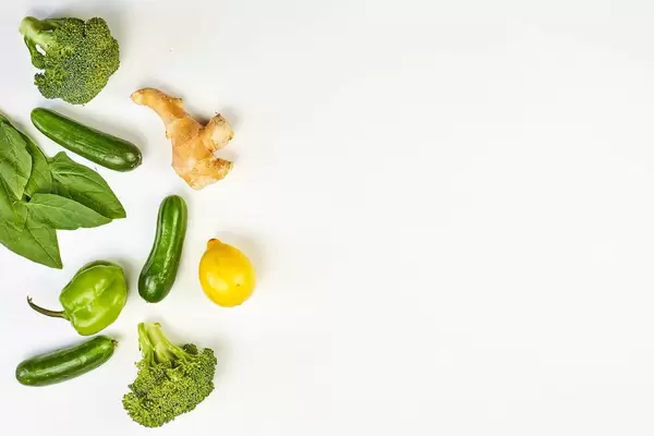 Variety of green vegetables with ginger and lemon on white