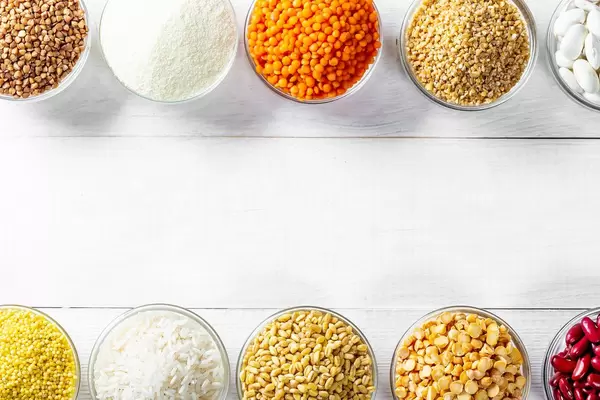 Various cereals in small bowls on a white wooden background with free space
