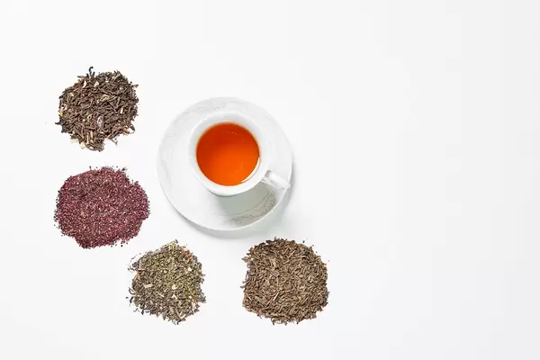Various types of dry tea leaves and a cup of red tea